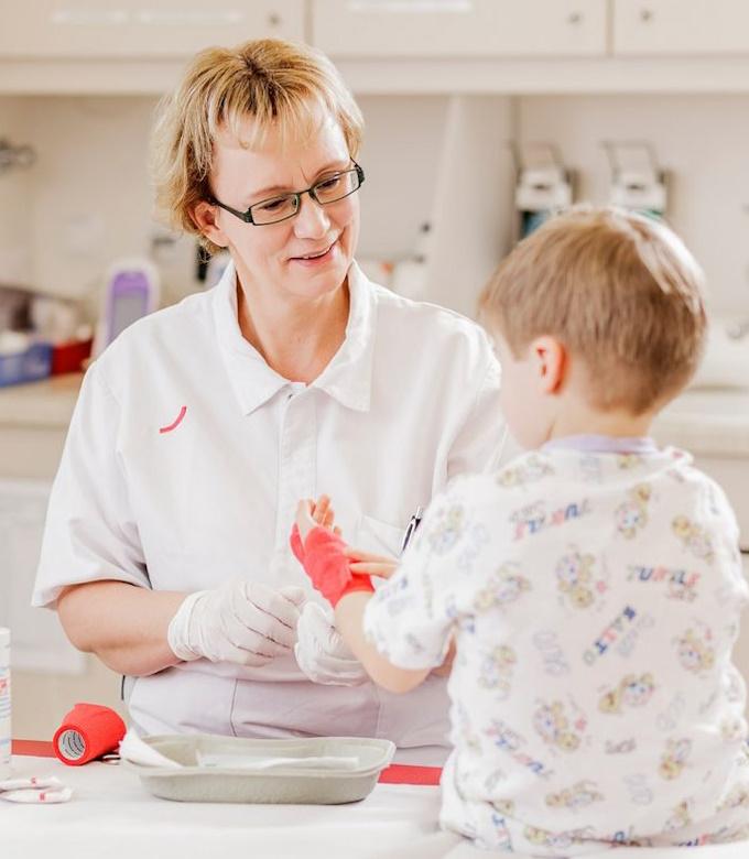 Pflegekraft verbindet einem Kleinkind die Hand