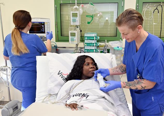 Zwei Pflegekräfte pflegen eine Patientin am Krankenhausbett
