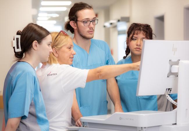 Krankenpflegerin erklärt Auszubildenden etwas zur digitalen Pflegedokumentation